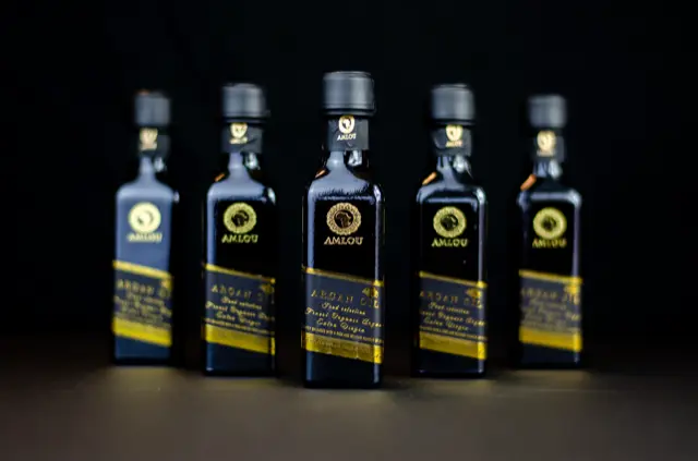 Sticlă de ulei de argan Amlou pe fundal cald, cu textură artizanală