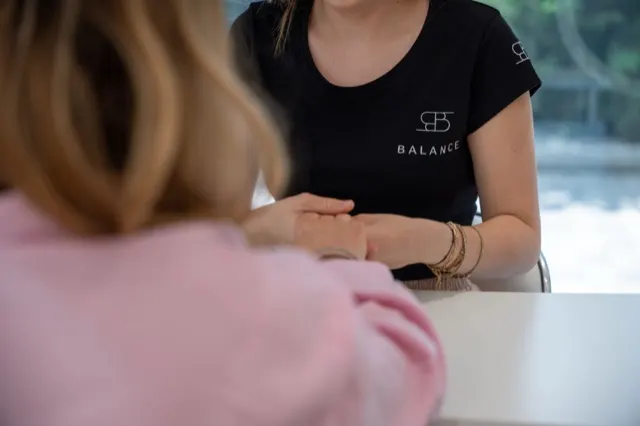Membră a echipei Balance, în tricou brandat, alături de o clientă